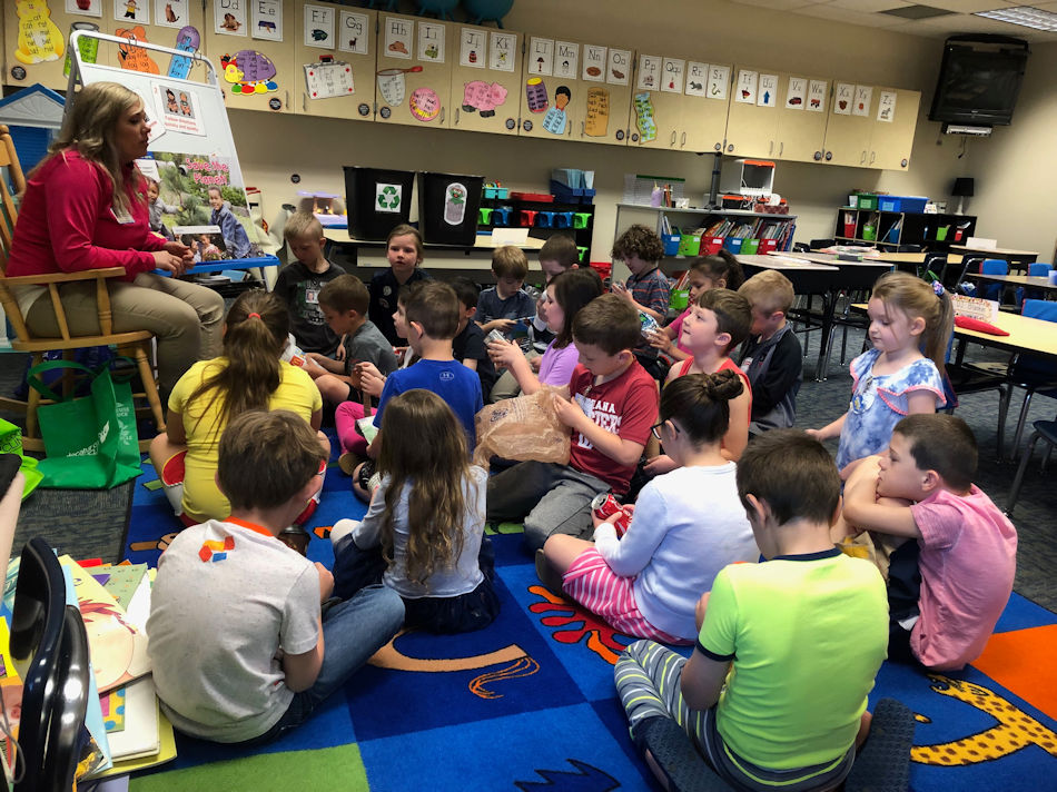 Children sitting listening to information on recycling