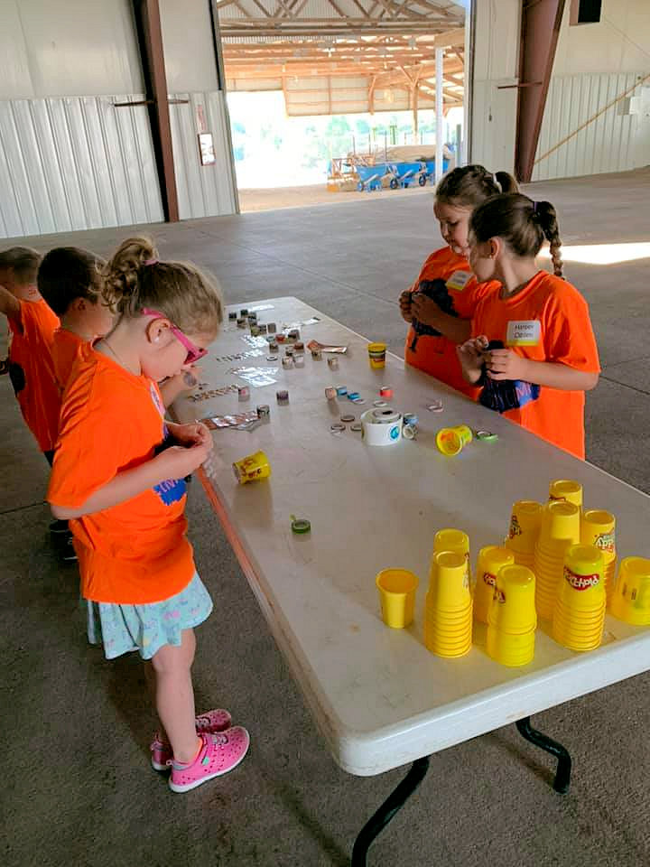 5 children standing at a table with Play-doh and toys